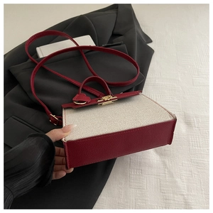 Detail view of contrast color handbag with beige canvas fabric and red leather accents