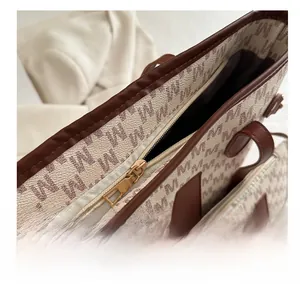 Close-up of smooth golden metal zipper and M-letter print texture on tote bag