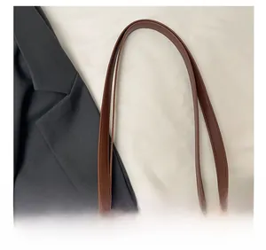 Gros plan des bandoulières en cuir marron avec coutures fines et texture mate
