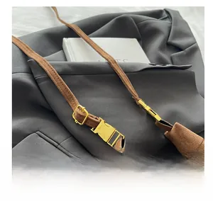 Detail of adjustable golden metal buckle on brown suede crossbody handbag strap