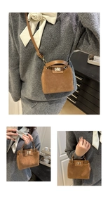 Detail view of a brown faux suede handbag with metallic twist lock and detachable strap
