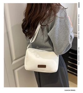 Close-up of white water-resistant crossbody bag featuring a FASHION logo leather patch