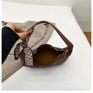 Detail of brown litchi leather handbag with silk scarf handle and gold zipper