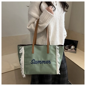 Détail du sac fourre-tout vert avec broderie Summer bleue et bordures à franges