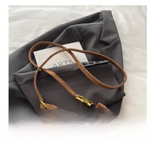 Detail of a brown suede crescent bag with golden buckle and wide shoulder strap