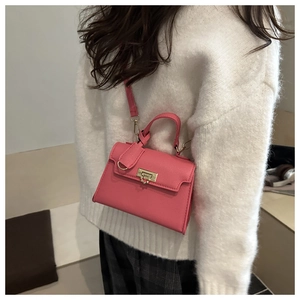 Pink mini leather handbag featuring gold twist-lock hardware worn with white sweater