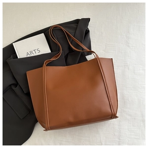 Brown vintage faux leather tote bag displayed with a black blazer and book for daily commute