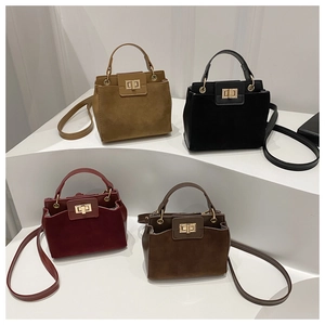 Detail view of four minimalist suede handbags featuring golden twist locks and adjustable straps