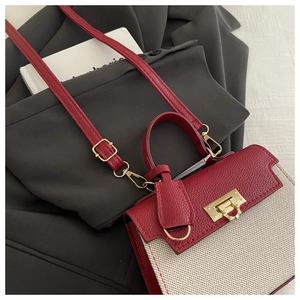 Detail of burgundy and cream leather bag with gold hardware on a stylish background