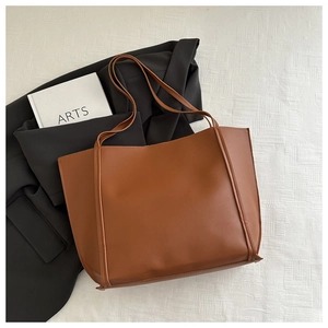 Detail of minimalist brown faux leather tote bag with slim shoulder straps for daily use