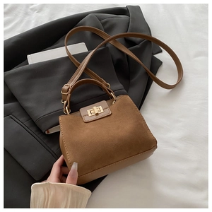 Close-up of brown suede tote bag with golden twist-lock and leather trim detail