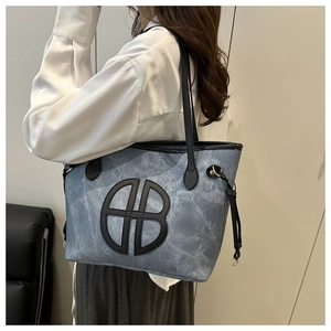 Side view of large denim tote bag with leather trim on model, showing size and fit
