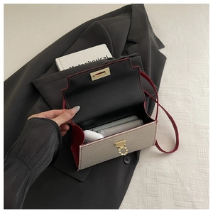 Detail showing the red leather interior and gold clasp of the cream textured mini handbag
