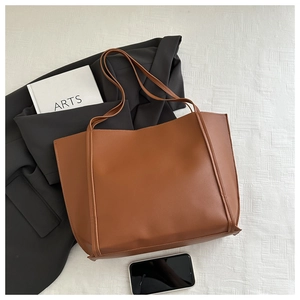 Flat lay of brown vintage leather tote bag styled with blazer and lifestyle props