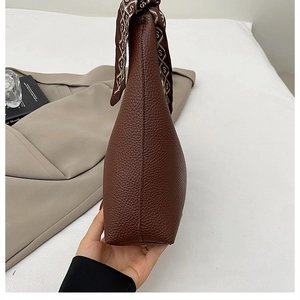 Detail of a brown lychee pattern leather shoulder bag with a stylish silk scarf handle