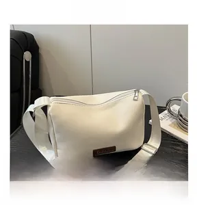 Détail du sac bandoulière en cuir PU blanc avec étiquette brune et large sangle