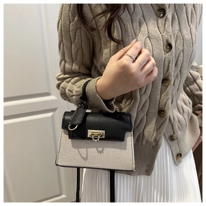 Detail of contrast stitch handbag featuring black leather flap and canvas body with gold lock