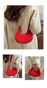 Détails de la sacoche demi-lune en daim rouge montrant les boucles dorées et la texture
