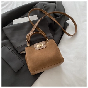 Close-up of brown suede and smooth leather handbag with gold twist lock and shoulder strap