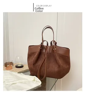 Détail du cabas marron café en daim et cuir lisse posé sur une table en verre