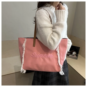 Détail du cabas en toile rose avec broderie Summer et pompons blancs sur un mannequin