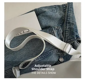 Gros plan d'une bandoulière en nylon réglable avec boucle argentée sur un sac blanc