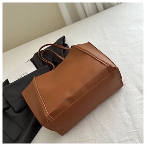 Detail shot of a large brown vintage leather tote bag on textured white fabric background