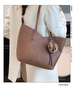 Detail of caramel pebbled leather tote bag featuring a stylish leopard faux fur pom pom charm