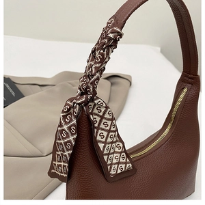 Detail of dark brown pebble leather hobo bag with silk scarf on the handle