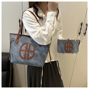 Detail of blue denim style tote bag with brown leather handles and matching pouch set