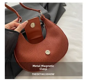 Détail de la fermeture magnétique et des plis verticaux du sac hobo rouge brique