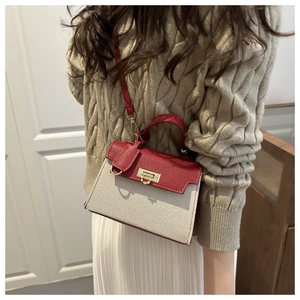 Detail of red and cream patchwork trapezoid handbag with gold rotating lock and strap