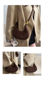 Vue détaillée du sac croissant en daim marron foncé avec fermoir doré sur un manteau