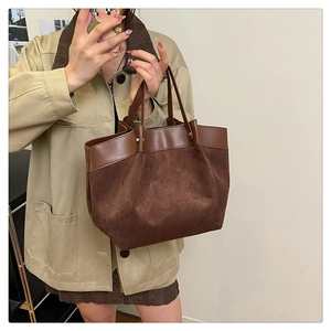 Détail d'un grand sac cabas marron foncé montrant un mélange cuir lisse et daim