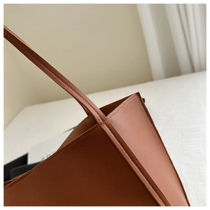 Close-up of brown leather tote bag handle with reinforced stitching and smooth edge oil finish