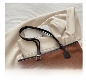 Détail du cabas en daim marron foncé avec bordure en cuir et boucles métalliques