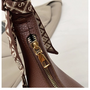 Detailed macro view of brown pebbled leather texture with a patterned silk scarf handle