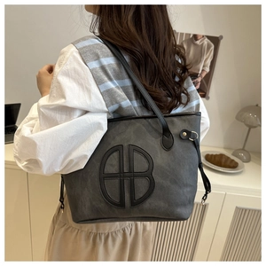 Macro detail of dark grey tote bag with embossed B logo and black leather strap