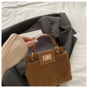 Detail of a brown leather shoulder bag featuring a gold square lock and mixed textures