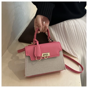 Detail of pink pebbled leather stitching and light gold metal buckle on a crossbody bag