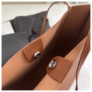 Detail of magnetic metal clasp and striped fabric lining on brown leather tote bag