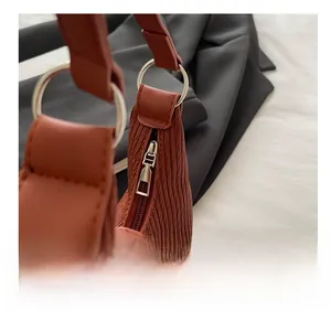 Détail macro de la fermeture éclair en métal argenté sur sac à bandoulière marron plissé