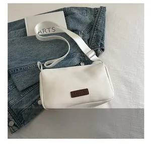 Détail de la sacoche blanche minimaliste avec sangle en tissu et étiquette marron
