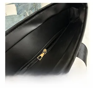 Detailaufnahme des goldenen Metallreißverschlusses und der Innenstruktur der schwarzen Tasche