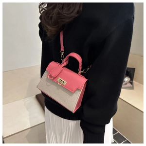 Pink and beige crossbody bag with gold lock shown on model with black knit top