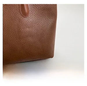 Close-up of caramel leather tote showing premium lychee grain texture and fine stitching