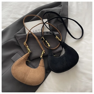 Détail de sacs hobo marron et noir en simili suède avec boucles dorées réglables