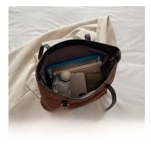 Vue intérieure montrant la grande capacité du sac cabas en daim marron avec objets quotidiens