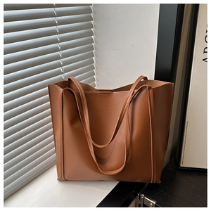 Detailed view of caramel brown faux leather tote bag with soft sunlight shadows