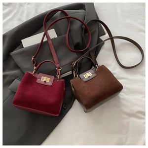 Close-up of matte suede and leather handbag detail with metallic twist lock closure
